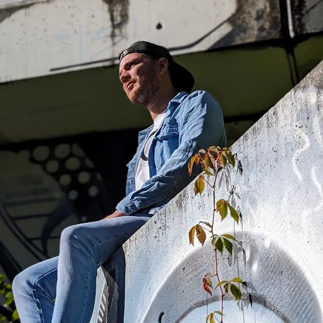 Martin sitzt auf einer Mauer mit Graffiti